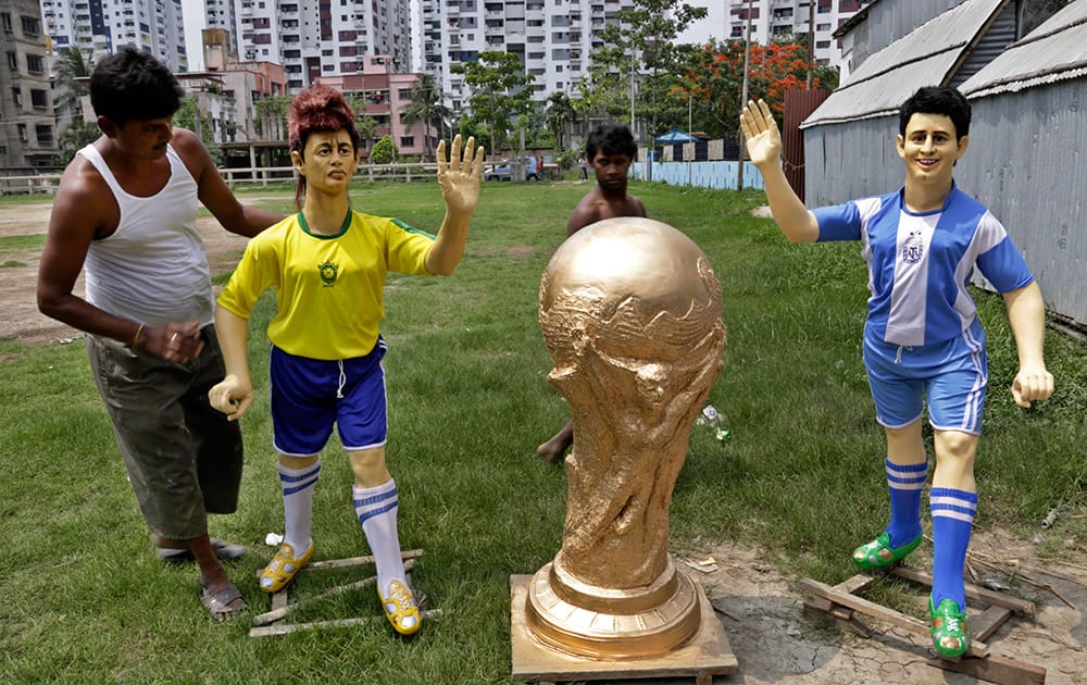 Sukumar Rudra Pal gives finishing touches to clay models of Brazil and Argentina soccer players beside a clay replica of soccer World Cup as they are made ready for display at a club in Kolkata.