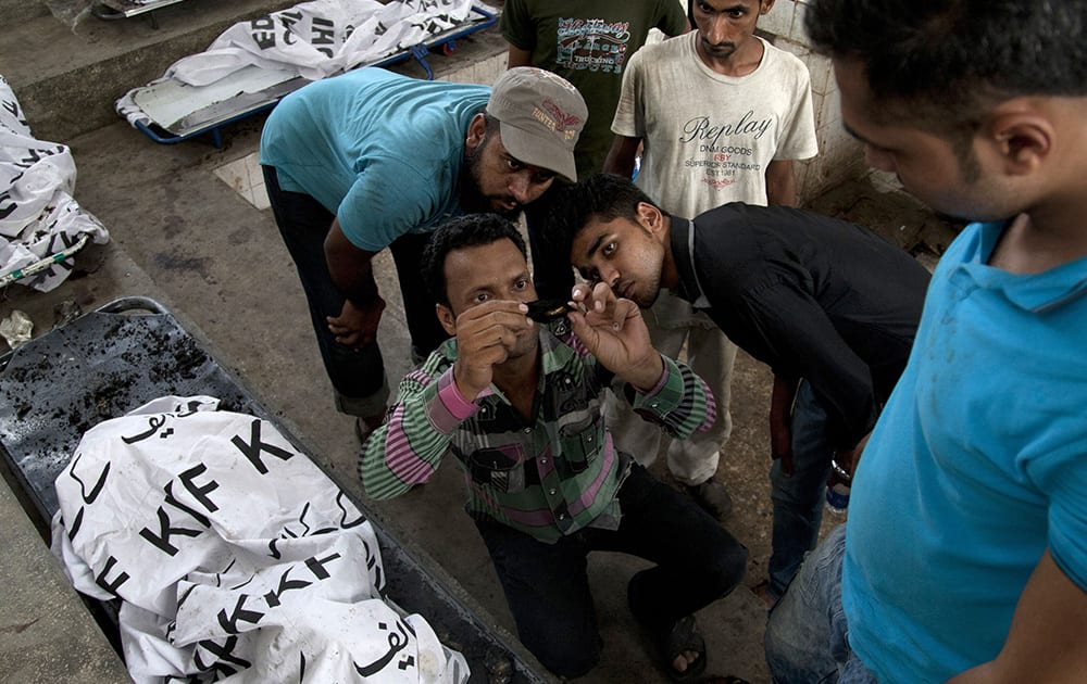 Pakistani family members try to read a burned identity card recovered from a victim of a deadly Taliban attack on Jinnah International Airport, last Sunday, in Karachi.