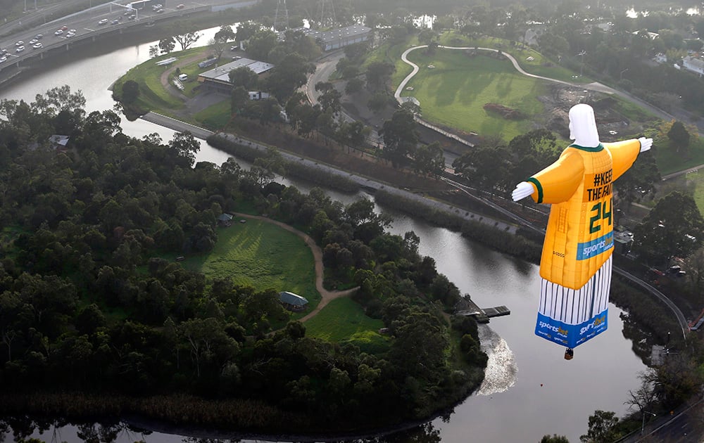 A hot air balloon in the likeness of Brazil’s Christ The Redeemer statute, wearing the colors of Australia`s soccer team floats over the Melbourne skyline.