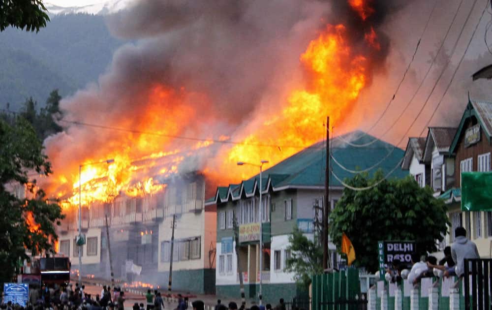 Locals and fire fighters try to douse flames from Hotels and shops during a major fire in which dozens of hotels and shopping malls were gutted, at Famous Tourist Resort in Pahalgam 90 km`s from Srinagar.