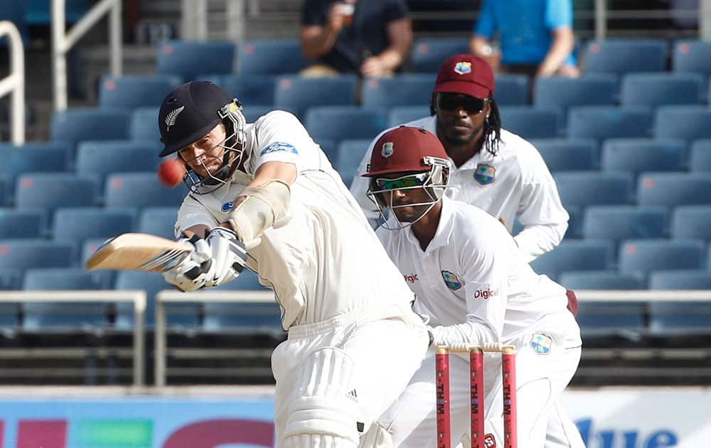 New Zealand`s batsman Tim Southee, left, drives for a six as West Indies wicket keeper Denesh Ramdin, center, and Chris Gayle, right back, looks on during the second day of their first cricket Test match in Kingston, Jamaica.