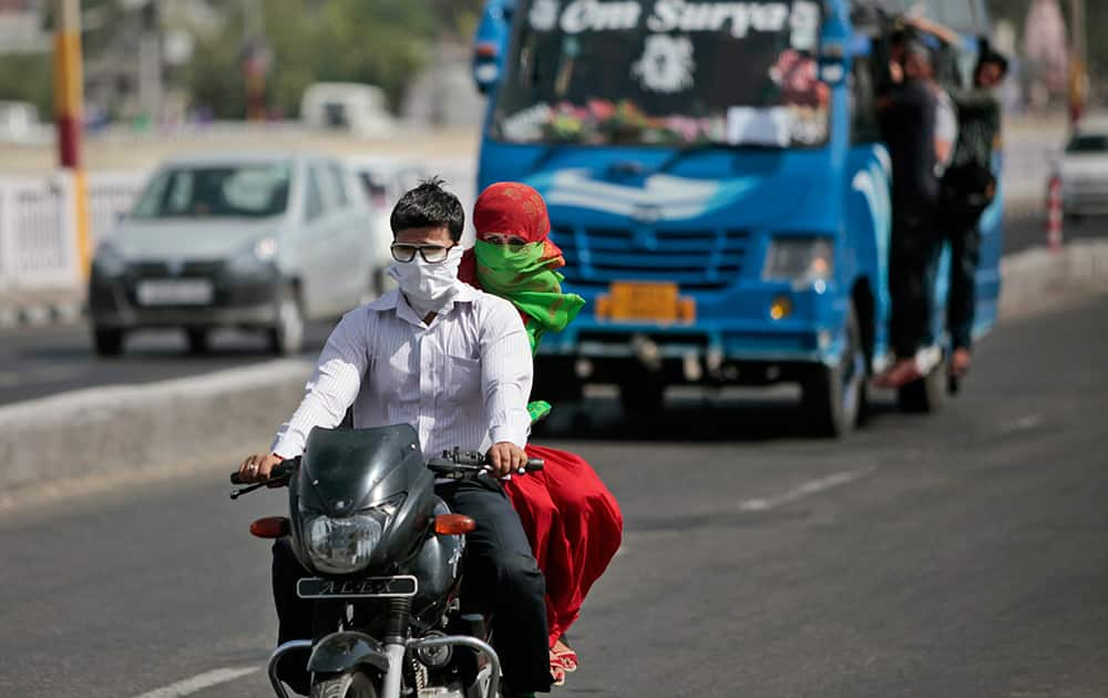 Commuters have their faces covered with scarves to keep from the heat as they ride on a motorbike in Jammu.