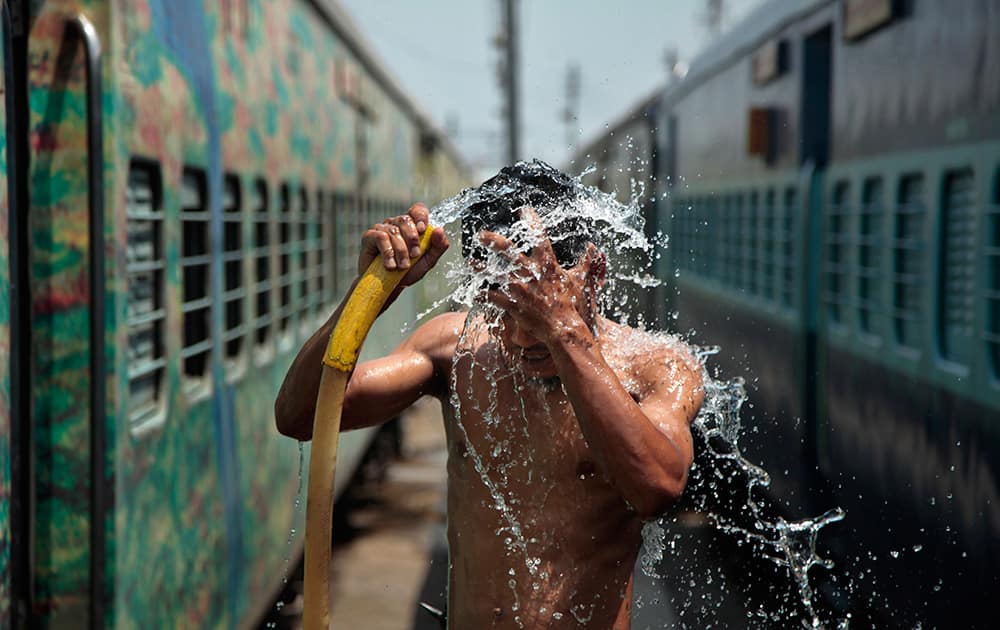 A man takes a shower at a railway station to cool himself down in Jammu.