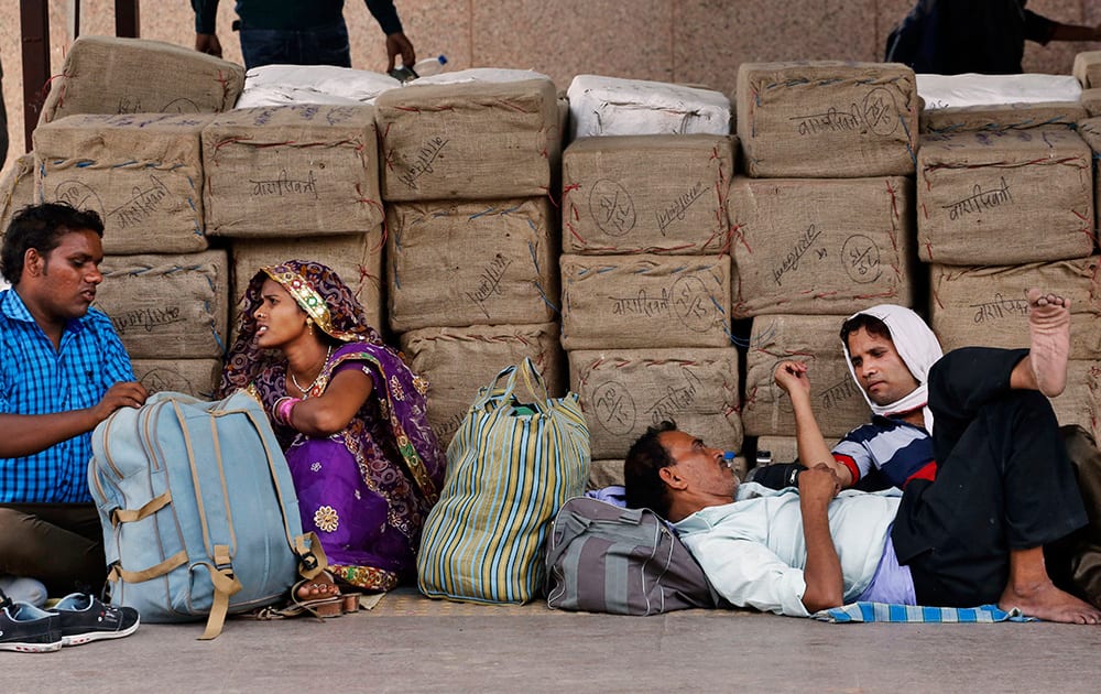 Commuters sit with their luggage on a train station platform on a hot summer day in Allahabad.