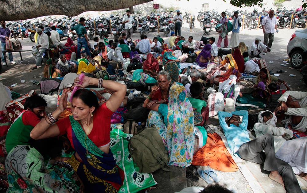 Hindu pilgrims on their way to the Vaishno Devi shrine, rest under the shade of trees outside a railway station in Jammu.