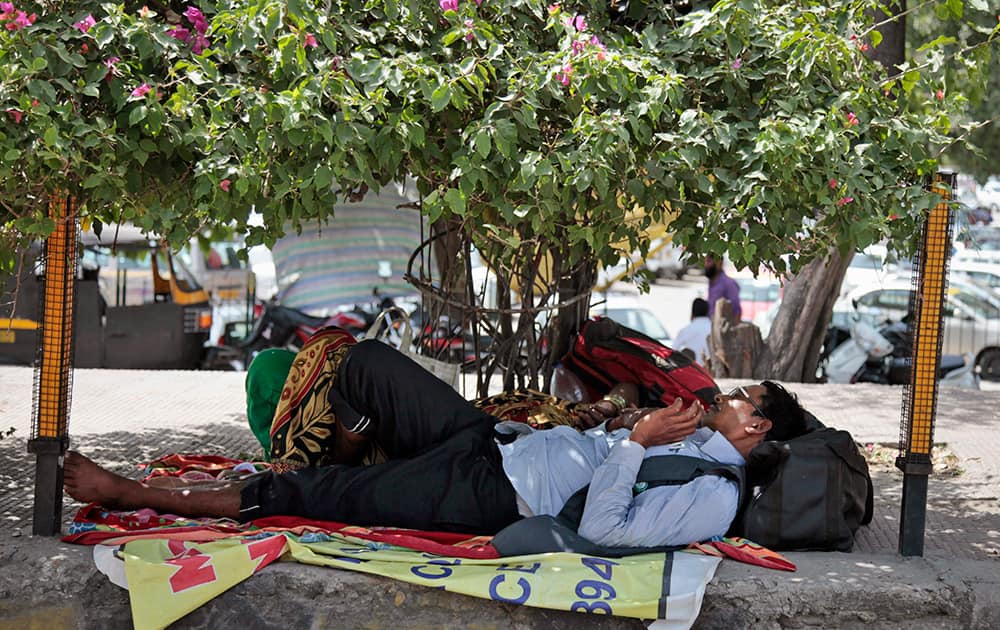 A pilgrim on his way to the Vaishno Devi shrine rests under the shade of a tree outside a railway station in Jammu.