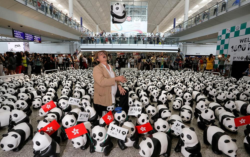 French artist Paulo Grangeon poses with part of the 1,600 paper pandas, created by him at the arrival hall of the Hong Kong International Airport during the opening of the month-long 