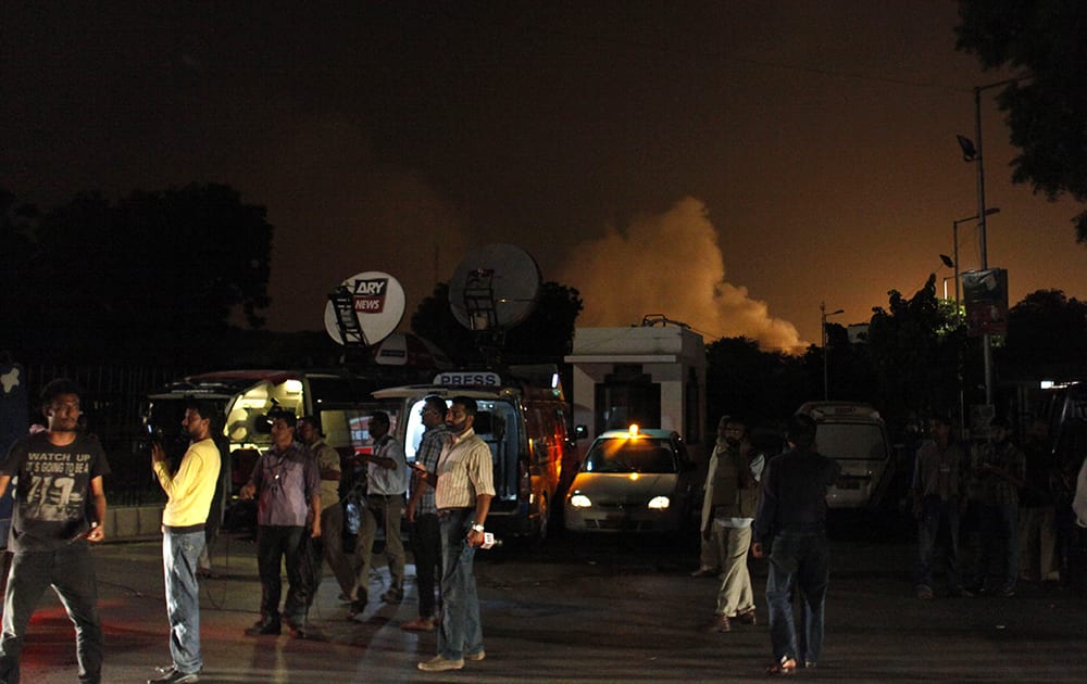 Reporters stand outside the Karachi airport terminal where security forces are fighting with attackers in Pakistan.