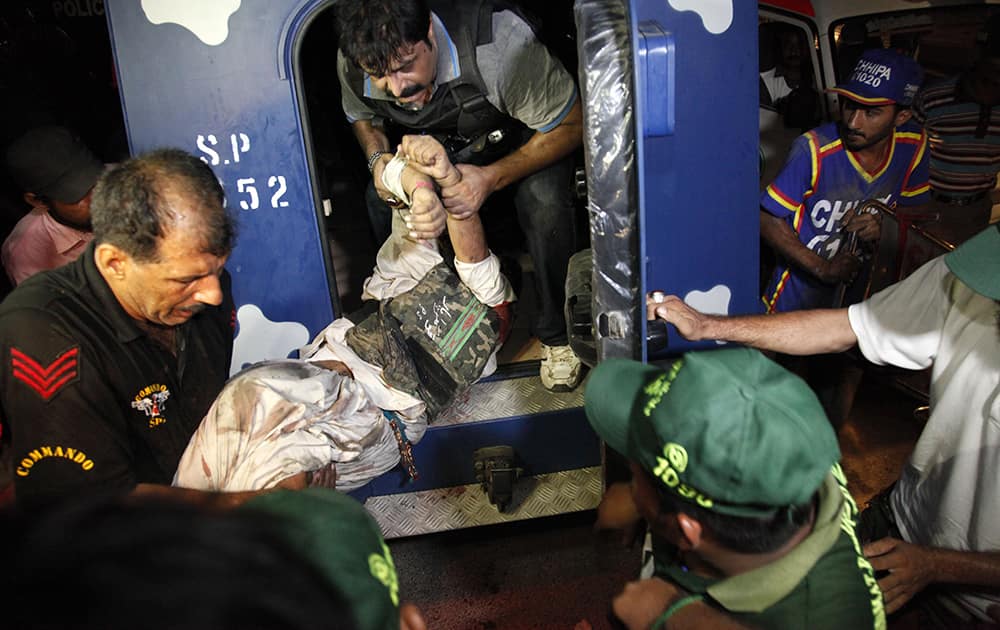 Pakistani police commandos help an injured colleague at Jinnah International Airport where security forces are fighting with gunmen who disguised themselves as police guards and stormed a terminal used for VIPs and cargo, in Pakistan. 