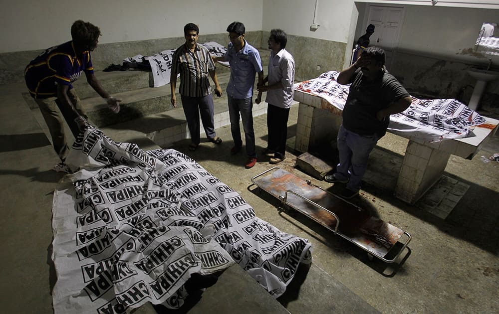 Volunteers look at dead bodies of people killed during an attack by unknown gunmen on Jinnah International Airport, in Karachi, Pakistan. 