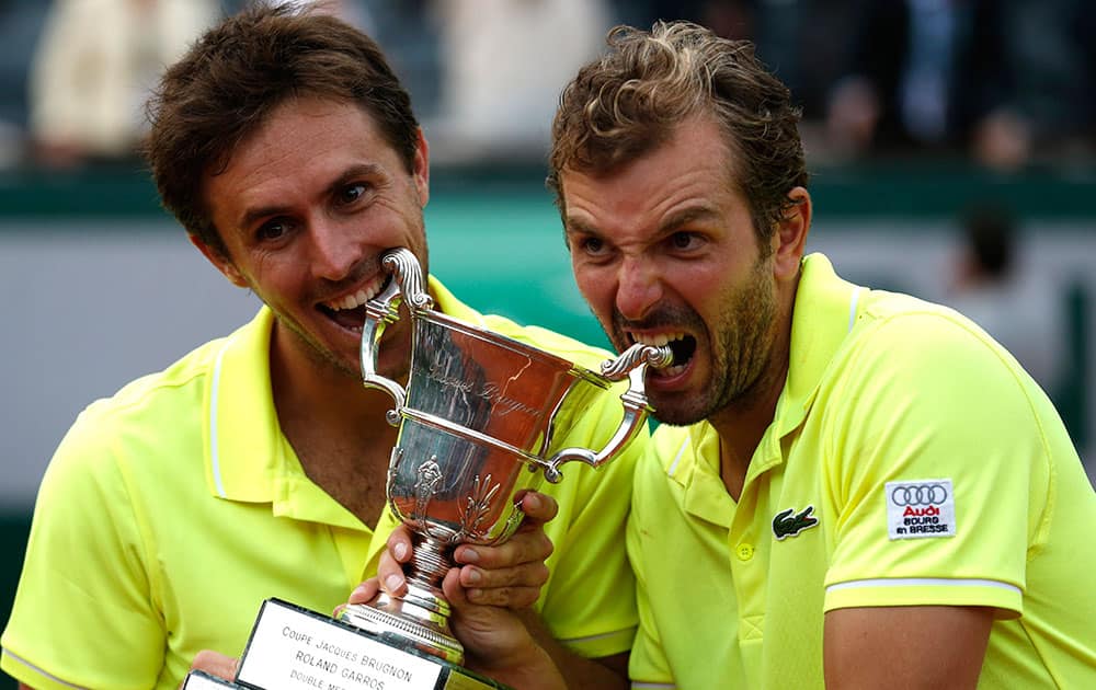 French pair Julien Benneteau, right, and Edouard Roger-Vasselin bite their trophy after defeating the Spanish pair Marcel Granollers and Marc Lopez during their men`s doubles final match of the French Open tennis tournament at the Roland Garros stadium, in Paris.