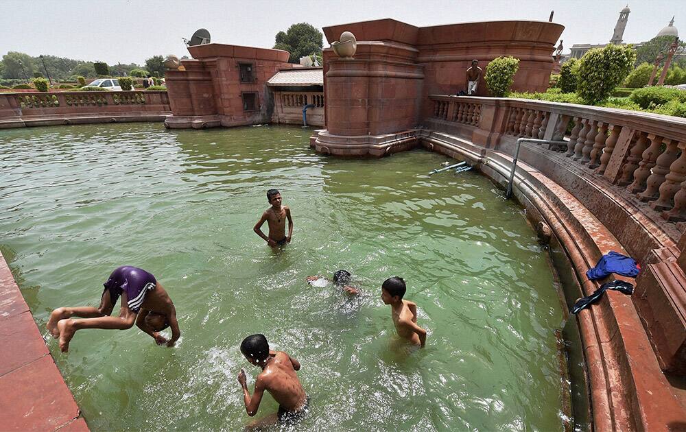 Children playing in a water near Vijay Chowk on a hot day in New Delhi.