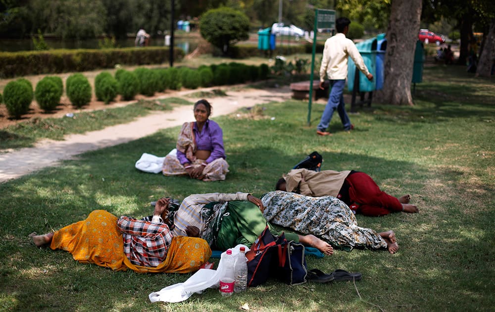 Municipal workers sleep on the grass under the shade of trees at a public park on a hot summer afternoon in New Delhi.