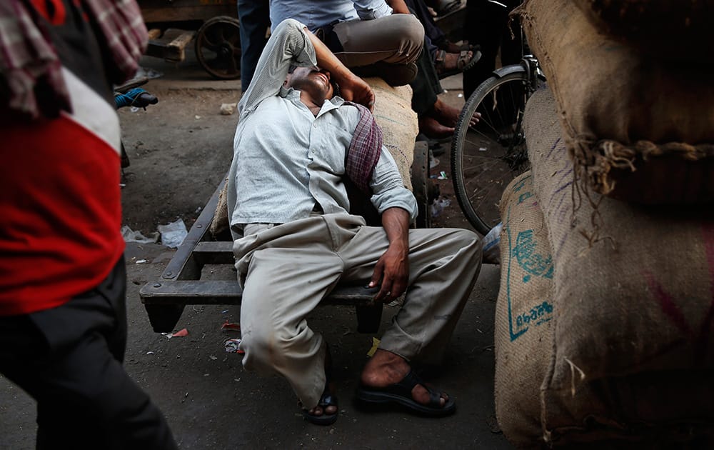 A laborer catches up on his sleep as he waits for his next delivery assignment at a wholesale market on a hot summer afternoon in New Delhi.