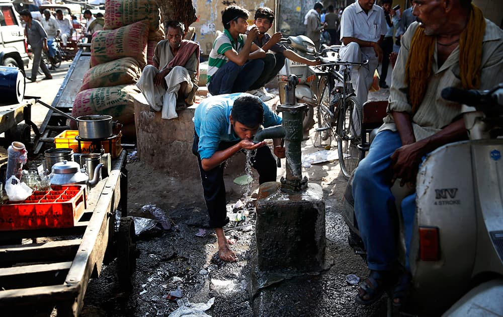 A laborer quenches his thirst from a roadside tube well at a wholesale market on a hot summer afternoon in New Delhi.