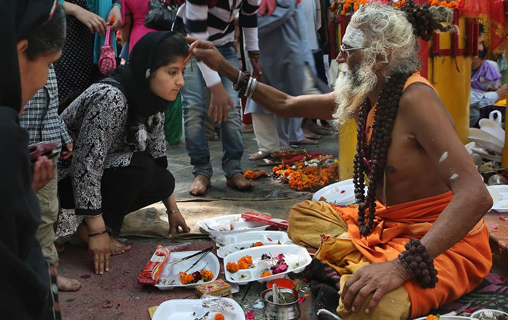 A priest applies vermilion on the forehead of a Hindu devotee at Kheer Bhawani temple during an annual Hindu festival in TullaMulla, 28 kilometers (17 miles) northeast of Srinagar.