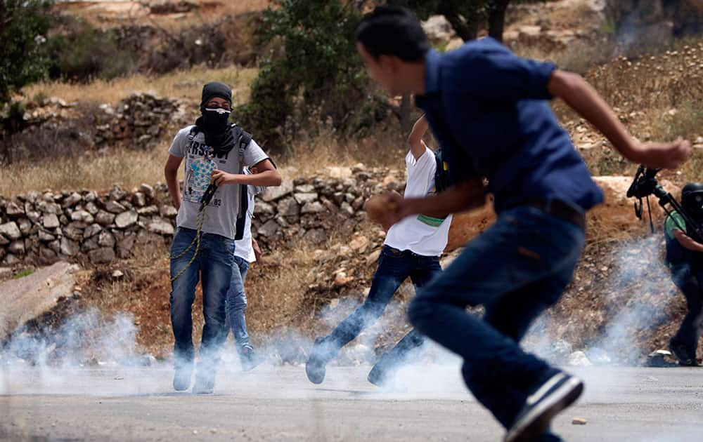 Palestinians run from tear gas during clashes with Israeli soldiers after a protest in support of Palestinian prisoners hunger striking since 42 days in Israeli jails, outside Ofer, an Israeli military prison near the West Bank city of Ramallah.