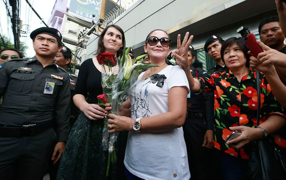 An unidentified Australian Embassy official, center left, receives a bouquet of flowers from a protester, center right, as another gestures beside her, during an anti-coup demonstration outside the Australian Embassy in Bangkok, Thailand.