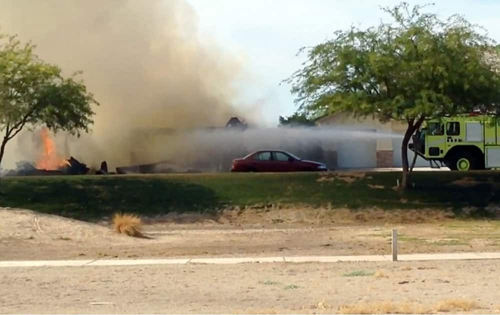 This frame grab made from video provided by Isaac Ramos shows firefighters putting out a fire caused when a military jet crashed in a residential neighborhood in Imperial, Calif. Witnesses say two houses caught fire after the crash.