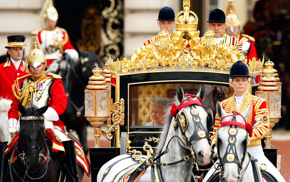 Queen Elizabeth II, centre, and The Duke of Edinburgh leaves Buckingham Palace, riding inside the new Diamond Jubilee State Coach, to deliver her speech at the Palace of Westminster, in London.