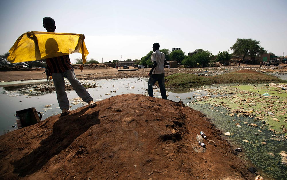 People collect disposable water for a car wash in El Fasher, North Darfur, Sudan. Environmental experts from the Sudanese government alert that frequent contact with standing water is dangerous to children`s health. June 5 is observed by the United Nations as World Environment Day.