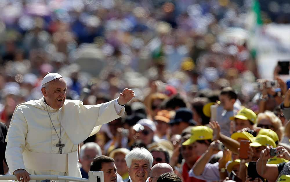 Pope Francis waves as he arrives in St. Peter`s Square for his weekly general audience, at the Vatican.