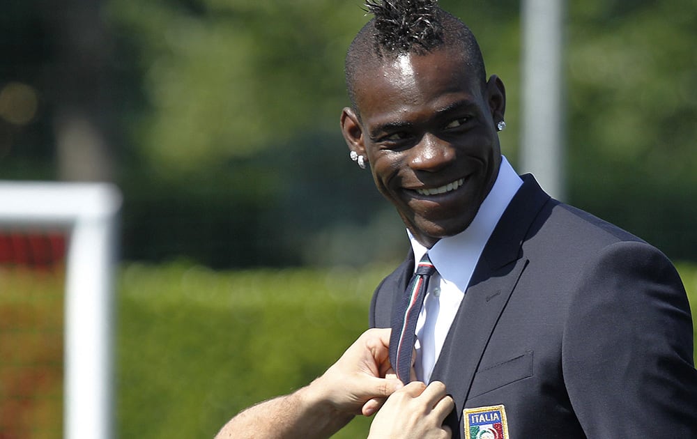 Italy forward Mario Balotelli has his tie adjusted at the Coverciano center, near Florence, Italy.