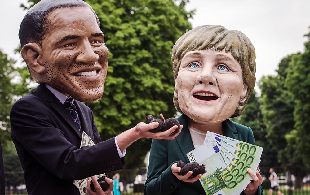 Oxfam demonstrators wearing masks of US President Barack Obama and German Chancellor Angela Merkel demonstrate for an energy secure world near the EU Council in Brussels.