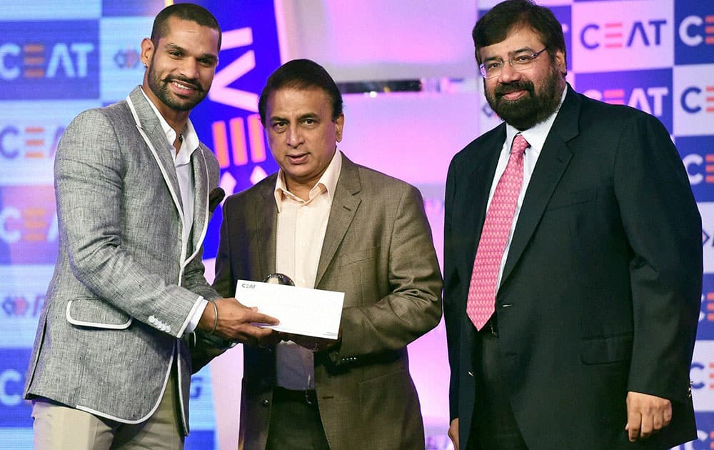 Cricketer Shikhar Dhawa receives an award from veteran cricketer Sunil Gavaskar and Industrialist Harsh Goenka during the CEAT International Cricket Awards 2014 in Mumbai.