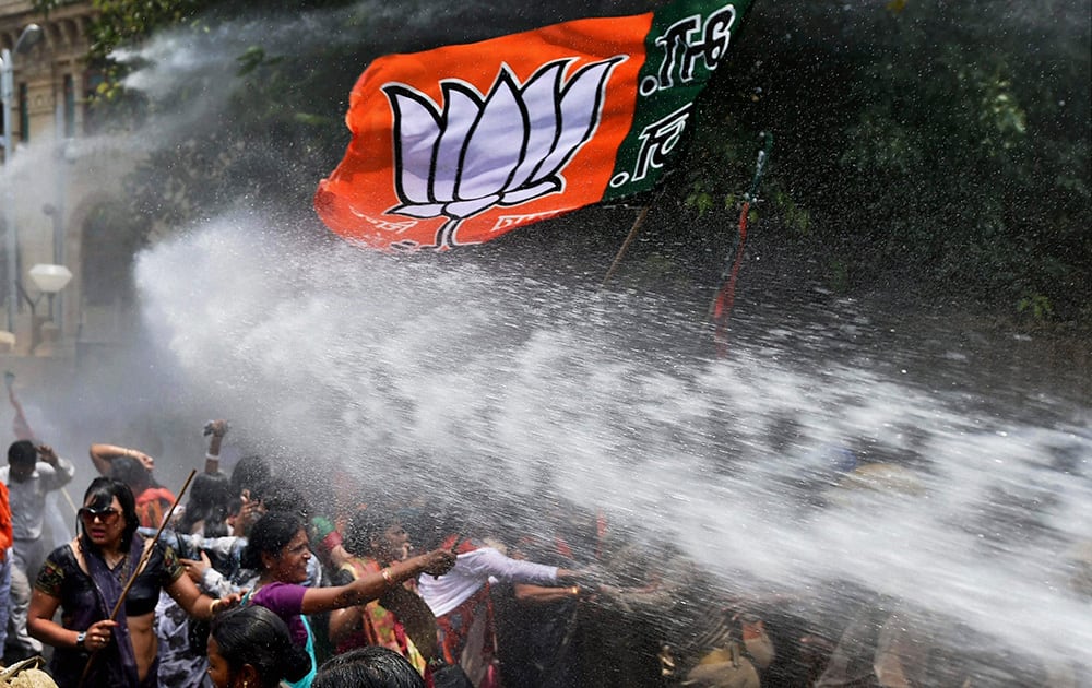 Women activists of Bharatiya Janata Party, flag seen top, face police water cannons as they demonstrate outside the office of Uttar Pradesh state chief minister Akhilesh Yadav, demanding that he crack down on an increasing number of rape and other attacks on women and girls, in Lucknow.