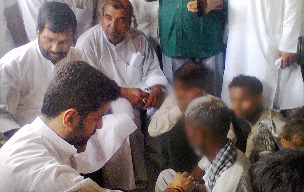 Minister of Consumer Affairs, Food and Public Distribution Ramvilas Paswan with his son Chirag Paswan meeting with the family members of two sisters who were gang raped and hanged from a tree at Katra Shahadatganj village, in Badaun district.