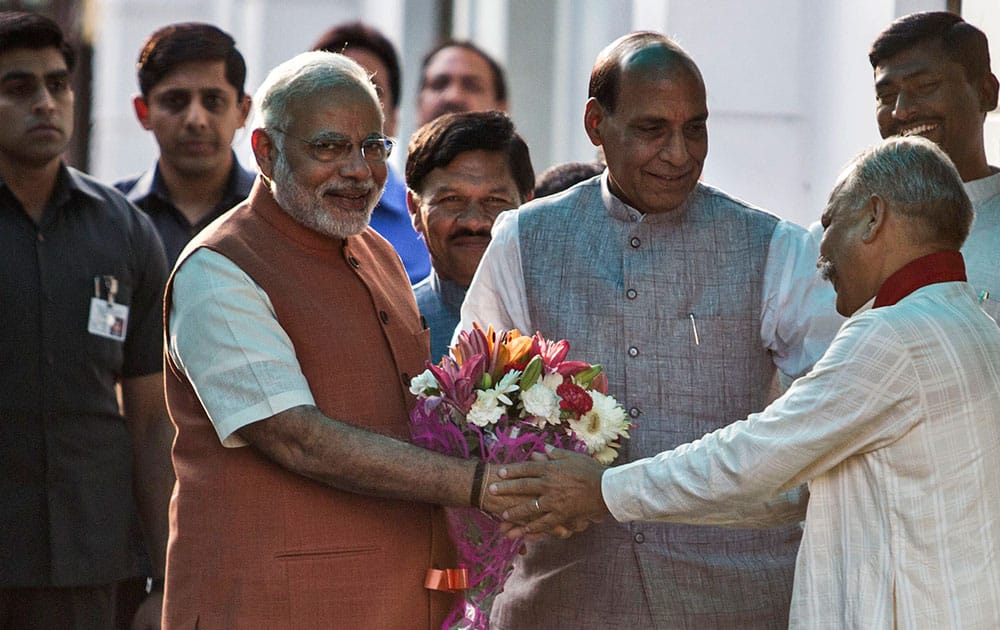 Prime Minister Narendra Modi, left, is received with flowers as he arrives for a meeting at the Bharatiya Janata Party (BJP) headquarters in New Delhi.