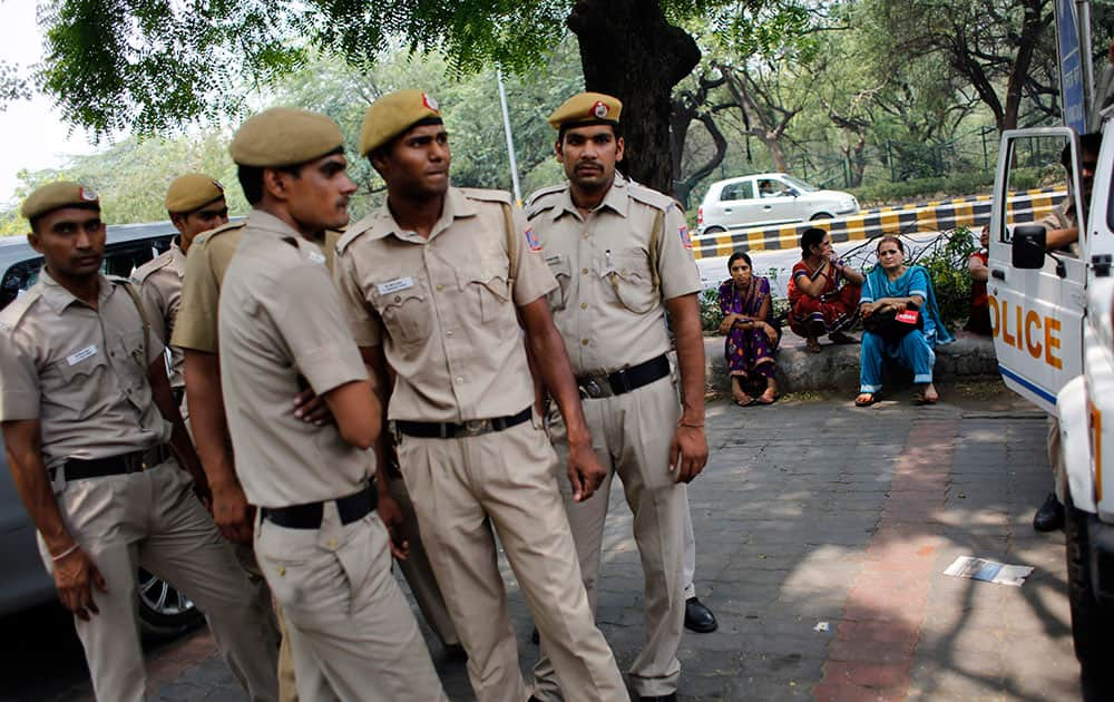 Delhi policemen stand guard as members of All India Democratic Women`s Association (AIDWA) sit on a pavement at the end of a protest against the gang rape of two teenage girls, in New Delhi.