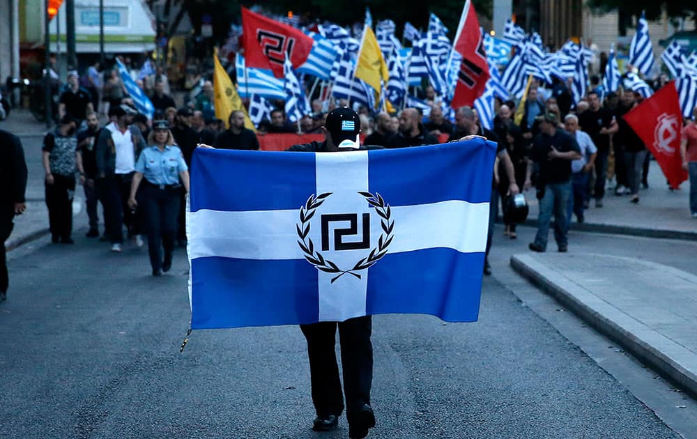 An extreme right Golden Dawn party supporter holds a flag emblazoned with the party symbol during a rally outside Parliament in central Athens.