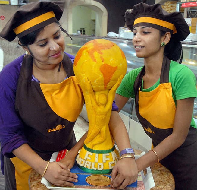 Female sweet vendors display a sweet in the shape of `FIFA World Cup 2014 to celebrate the upcoming mega event at a sweet shop in Kolkata.