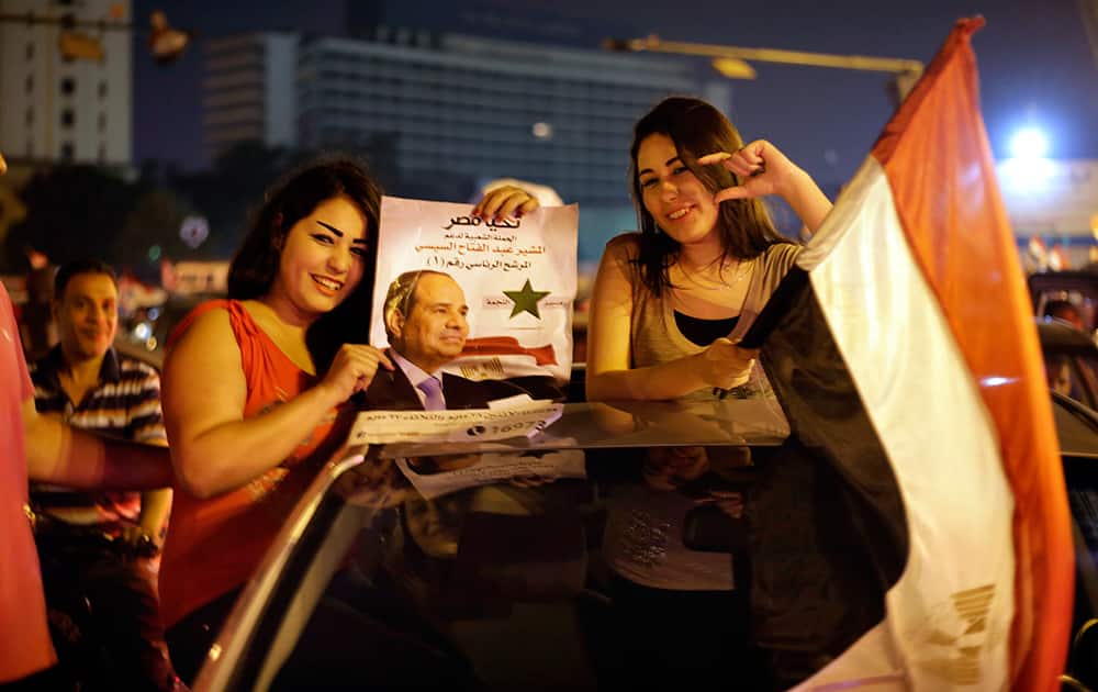 Supporters of presidential hopeful Abdel-Fattah el-Sissi, Egypt`s former military chief, hold his poster and a national flag during a celebration at Tahrir Square in Cairo.