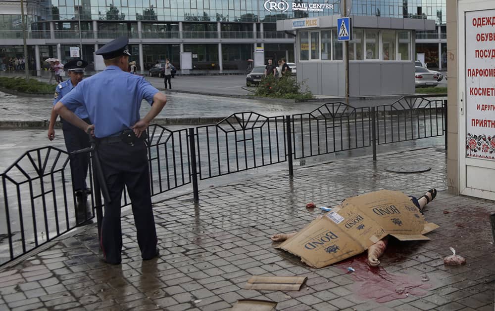 Police officers stand next to a body of an unidentified woman killed by shrapnel following a shelling from Ukrainian government forces, outside railway station in Donetsk, Ukraine.