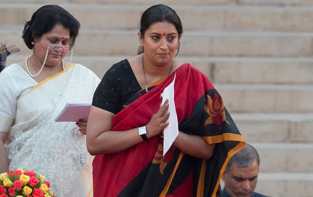 Smriti Irani greets the audience after she takes the oath of office at the presidential palace in New Delhi.