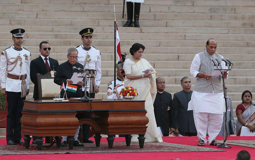 President Pranab Mukherjee, third left, administers the oath of office to Cabinet Minister Rajnath Singh, right, at the presidential palace in New Delhi.