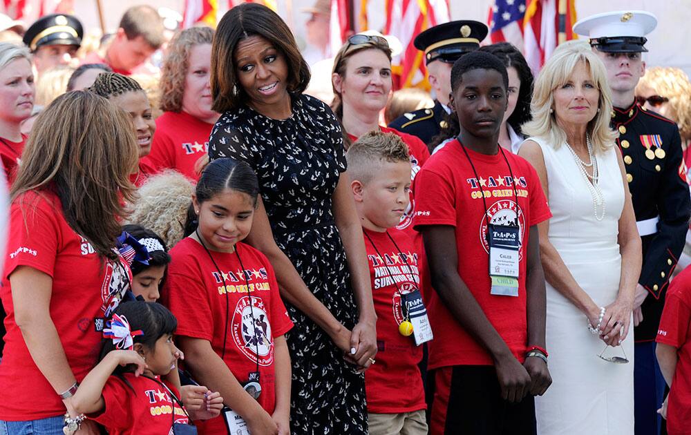 First lady Michelle Obama and Dr. Jill Biden, stand with children of fallen service members who traveled to Washington to participate in the Tragedy Assistance Program for Survivors (TAPS) 20th Annual Good Grief Camp as they wait for President Barack Obama to speak at Arlington National Cemetery in Arlington, Va.