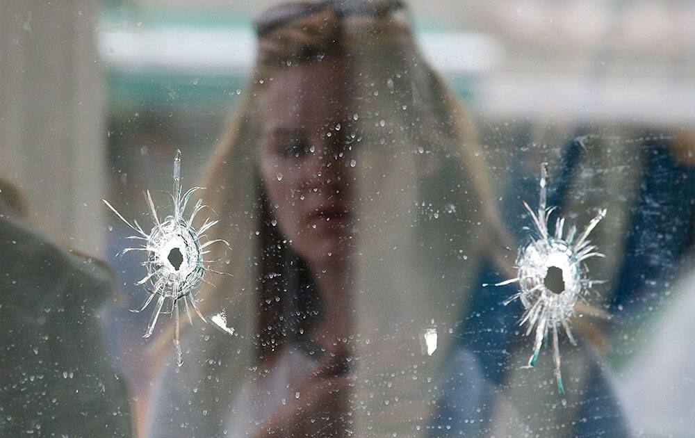 A woman looks at the bullet holes on the window of IV Deli Mark where Friday night`s mass shooting took place by a drive-by shooter in Isla Vista, Calif. The shooter went on a rampage near a Santa Barbara university campus that left seven people dead, including the attacker, and seven others wounded, authorities said Saturday.