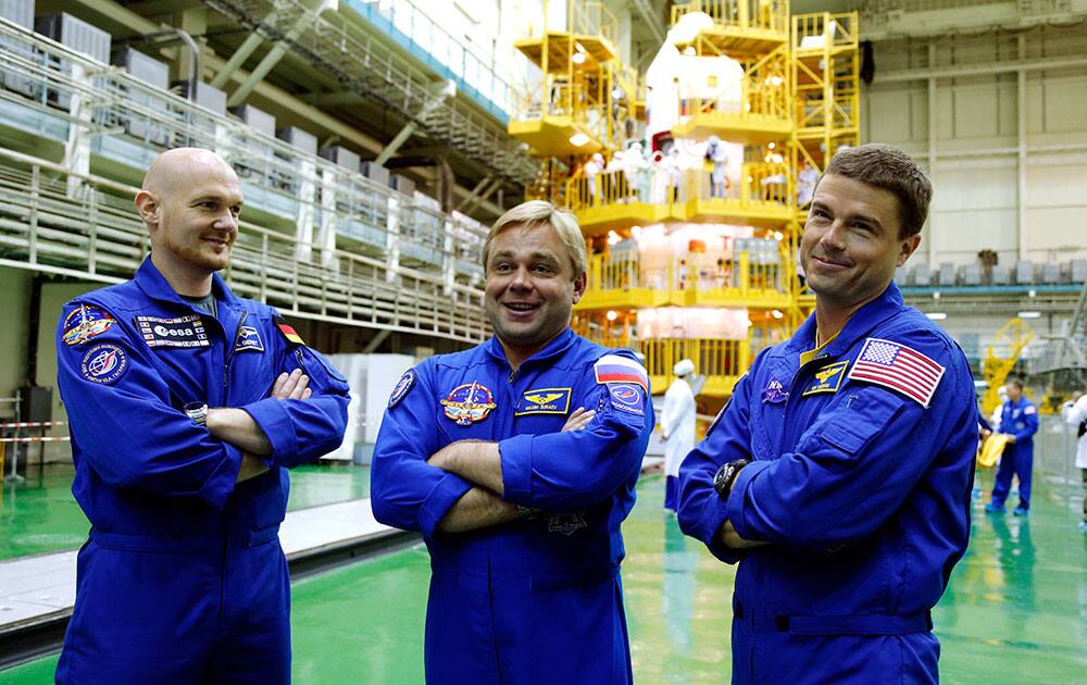 European Space Agency`s astronaut Alexander Gerst, left, Russian cosmonaut Maxim Suraev, center, and NASA astronaut Gregory Reid Wiseman, members of the next mission to the International Space Station, stand next to a Russian Soyuz TMA-13M spaceship during training in an assembly shop in Russian leased Baikonur cosmodrome, Kazakhstan.