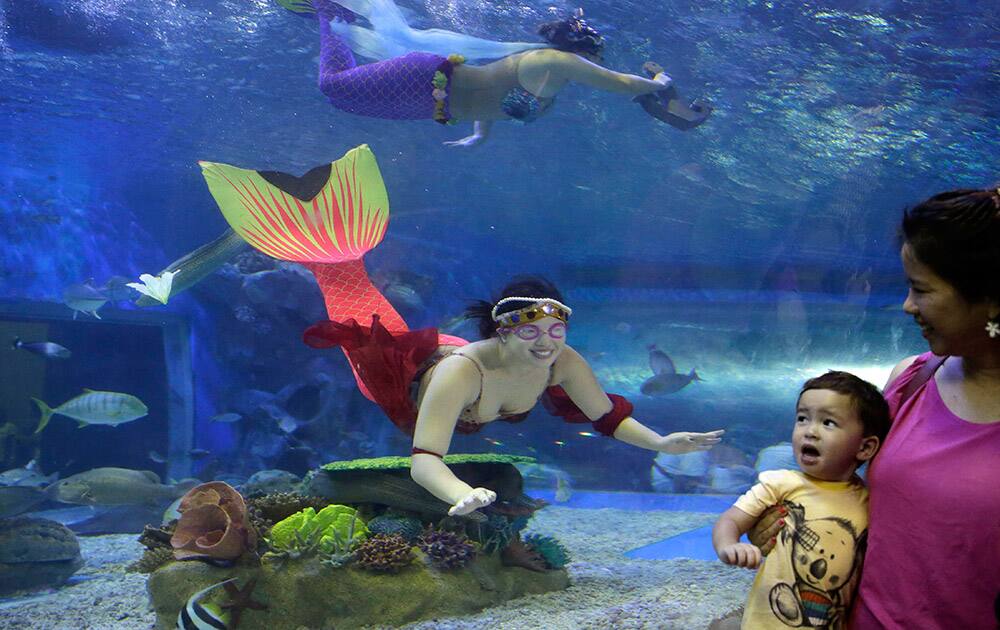 A diver, dressed as a mermaid, prepares to interact with a child following a performance to celebrate a religious festival known as `Santacruzan` at the Manila Ocean Park, the country`s largest oceanarium.