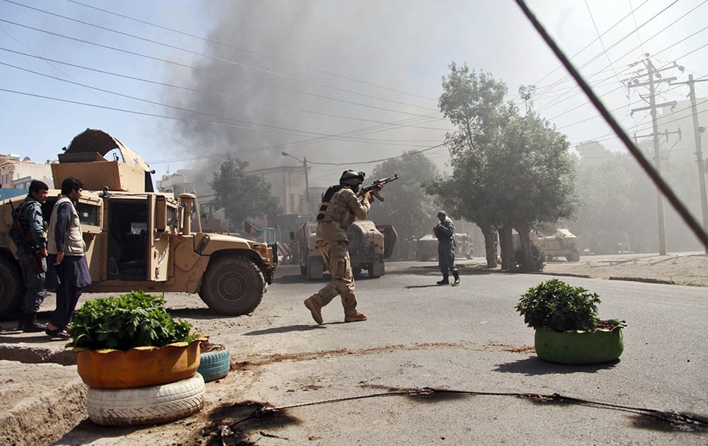 An Afghan special forces soldier, center, aims his weapon at at the site of a clash between insurgents and security forces on the Indian Consulate in Herat, Afghanistan.