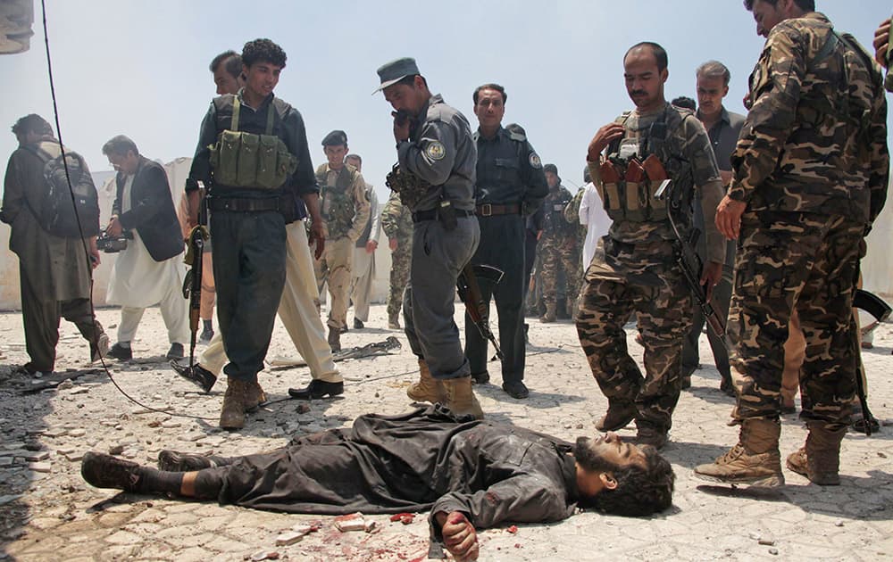 Afghan security forces gather around the lifeless body of an insurgent at the site of a clash between insurgents and security forces at the Indian Consulate in Herat, Afghanistan.