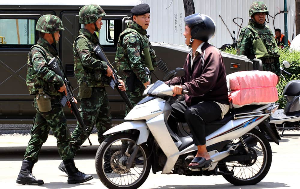 A motorcyclist rides past Thai soldiers patroling on a street in Bangkok, Thailand. Thailand`s ruling military on Friday summoned the entire ousted government and members of the politically influential family at the heart of the country`s long-running conflict, a day after it seized control of this volatile Southeast Asian nation in a non-violent coup.