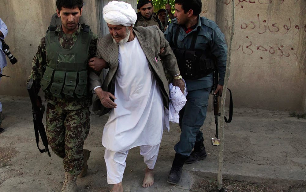 An Afghanistan`s National Army (ANA) soldier assists an old man at the site of a clash between insurgents and security forces at the Indian Consulate in Herat, Afghanistan.