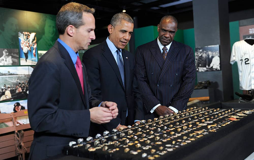 President Barack Obama, accompanied by Baseball Hall of Fame President Jeff Idelson, left, and baseball hall of fame member Andre Dawson, looks over a collection of World Series rings during a tour the Baseball Hall of Fame in Cooperstown, N.Y.