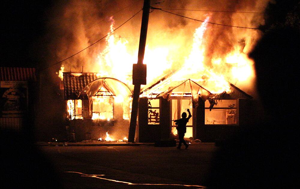 A pro-Russian fighter takes a photo on his cell phone of a burning cafe after impact of a mortar bomb, during fighting between Ukrainian government troops and pro-Russian militants at a checkpoint near the major highway which links Kharkiv, outside Slovyansk, Ukraine.