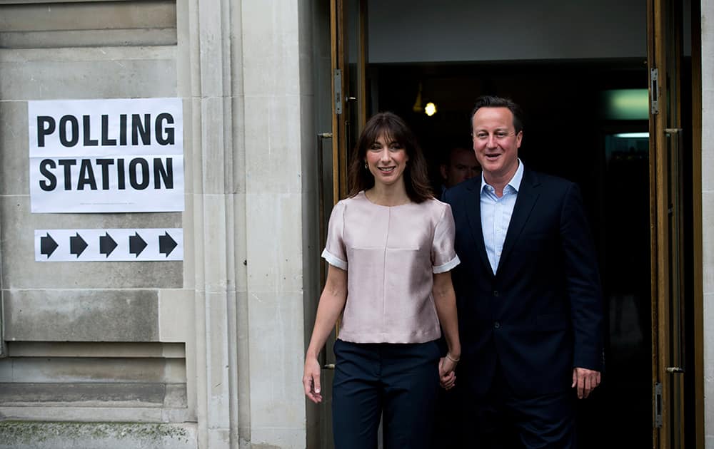 Britain`s Prime Minister and leader of the Conservative Party David Cameron and his wife Samantha pause to pose for photographers and television cameras as they leave after casting their votes at a polling station in central London.